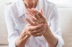 [Translate to Spanish:] Person in white blouse holding left hand with right hand